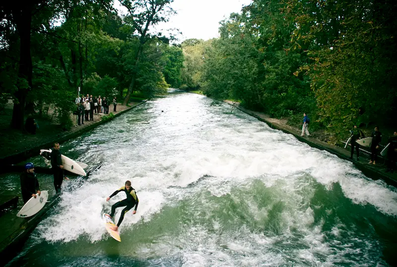 A surfer riding the Eisbach river wave in the middle of Munich